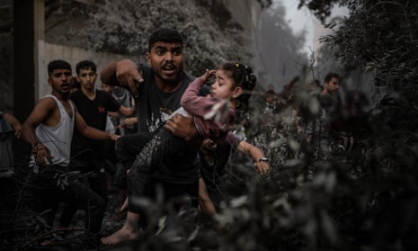 A man carries a girl as Palestinians conduct a search and rescue operation after the Israeli attacks on Al-Maghazi refugee camp in Deir Al Balah.
