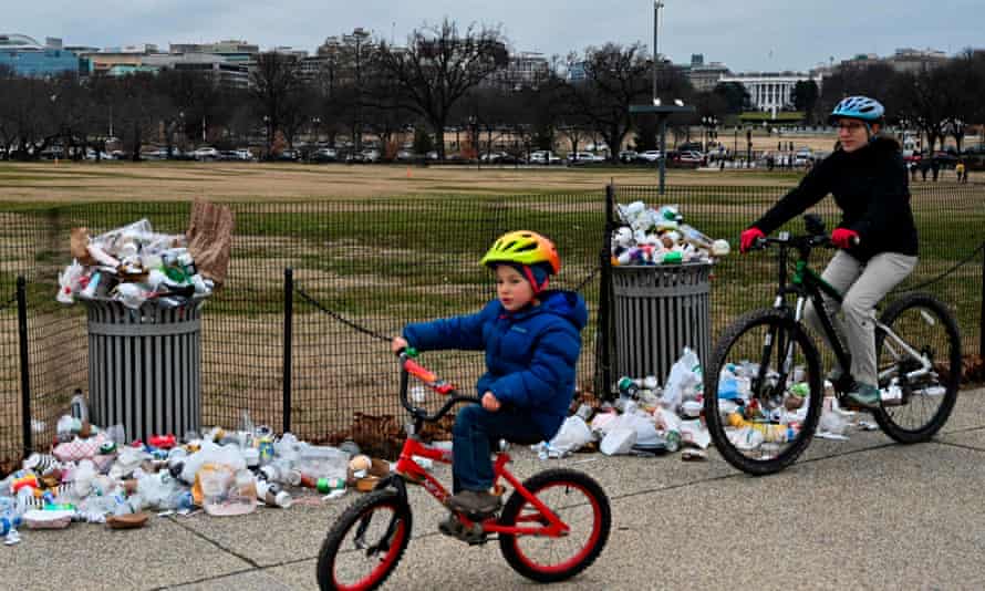People bike past trash uncollected on the National Mall, due to the partial shutdown of the US government.