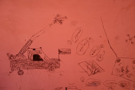 A child’s drawings on a wall of pickup trucks mounted with guns