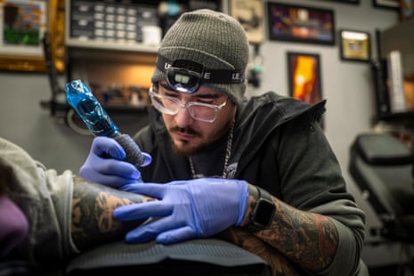 Tattoo artist at work on a client’s arm.