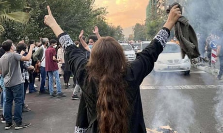 A female protester in Tehran with back to camera, arms aloft