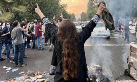 A female protester in Tehran with back to camera, arms aloft