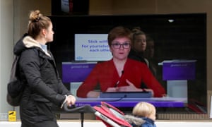 A member of the public walking a shop in Edinburgh with a screen in the window showing Nicola Sturgeon addressing the Scottish parliament yesterday.