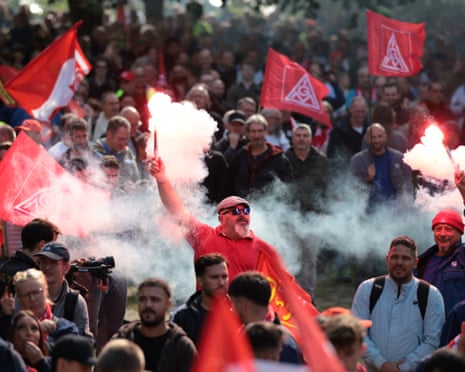 Trabalhadores acendem sinalizadores e agitam bandeiras do sindicato industrial IG Metall enquanto protestam contra cortes de empregos em uma fábrica da VW em Hanover