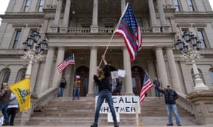 People hold flags and placards as hundreds of supporters of the Michigan Conservative Coalition protest against the stay-at-home order.