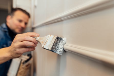 A man painting a wall in a house.