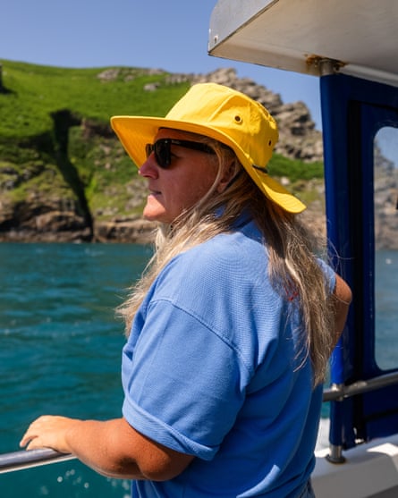 A woman with long fair hair, wearing sunglasses and a yellow hat, on a boat off Lundy, Devon, on a pleasant summer day.
