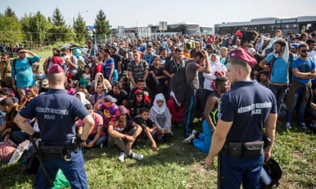 Hungarian police monitor a large group of migrants and refugees at a border crossing between Hungary and Croatia at Beremend.