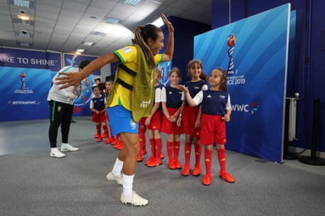Marta of Brazil high fives match mascots in the tunnel ahead of a group C match between Brazil and Jamaica at Stade des Alpes.