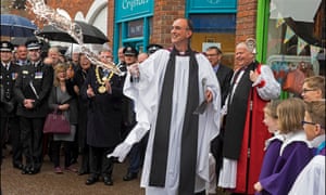 Reverend Kelvin Inglis of St. Thomas Church throws cleaning water at the area where the Skripals were found, overseen by Salisbury Bishop Nick Holtam and representatives of the city, police and firefighters.