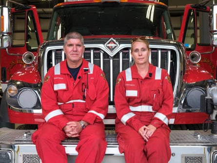 Fox Creek volunteer firefighters Wade and Angel Martineau sitting on the front bumper of the rescue unit.