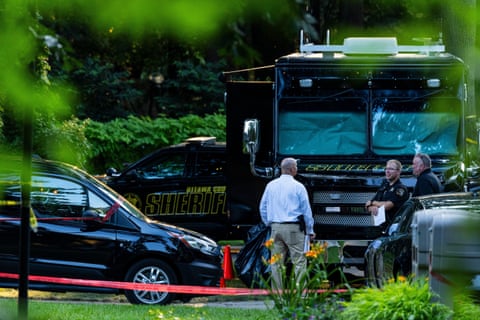three men stand near law enforcement vehicles outside