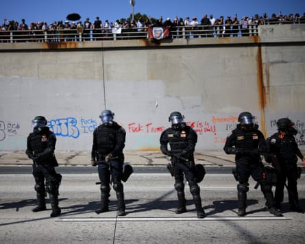 Demonstrators look at police officers from above during a protest against federal immigration sweeps in downtown Los Angeles.
