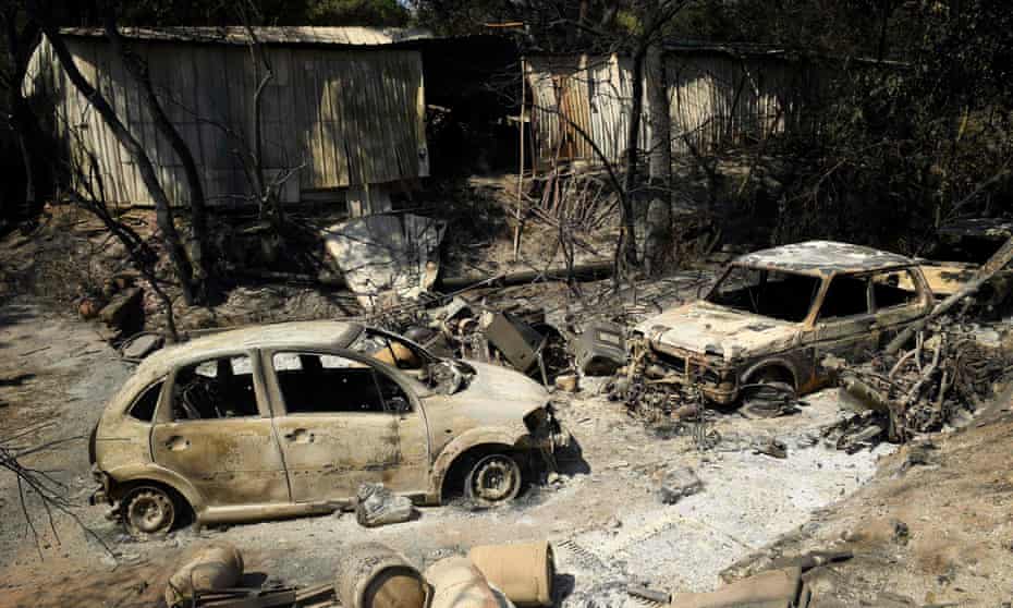Burnt-out cars outside a house destroyed by the wildfire near the village of Grimaud in Var, southern France