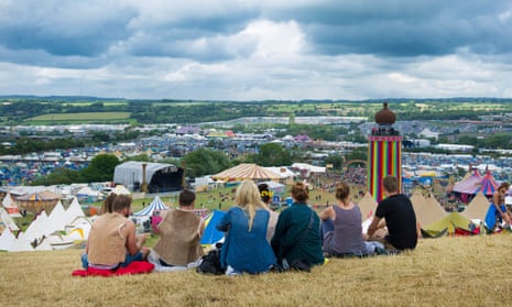 Revellers sit and overlook the festival grounds during Glastonbury 2014.