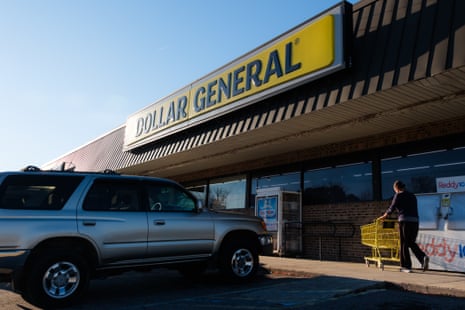A shopper pushes a cart toward a Dollar General storefront under its yellow sign