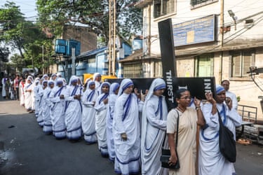 Image 15: A procession of nuns carry a large cross along a street