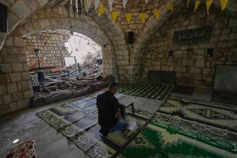 A man reads a copy of the Qur’an inside a damaged mosque.