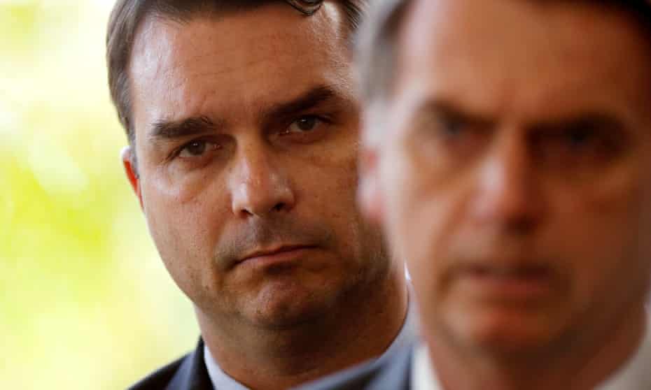 Flávio Bolsonaro, pictured behind his father, President Jair Bolsonaro, employed the wife and the mother of the alleged leader of Rio de Janeiro’s most powerful paramilitary gang for more than a decade.