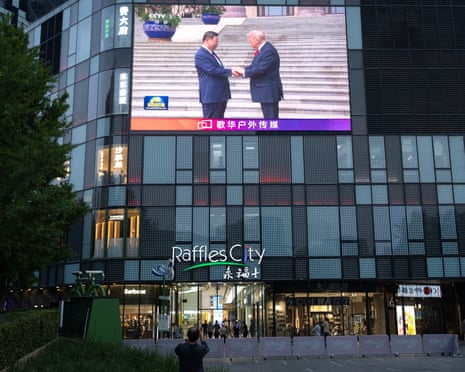 A broadcast is shown on a large screen in Beijing of Xi Jinping and Donald Trump meeting at their high-stakes summit, which finishes on Friday