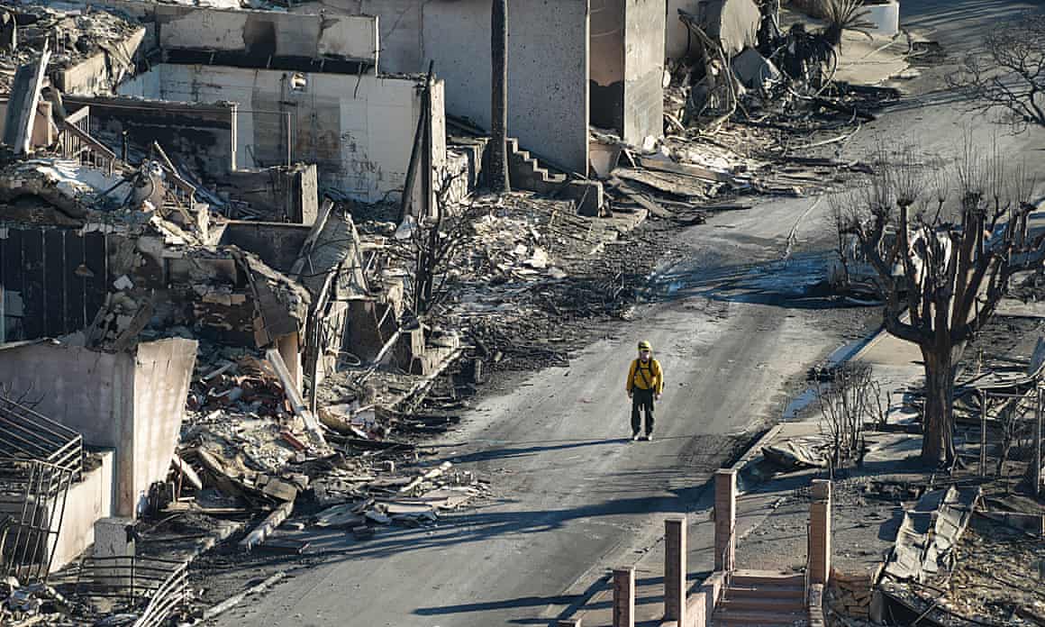 A firefighter walks through a neighborhood devastated by fire in Los Angeles on Tuesday.