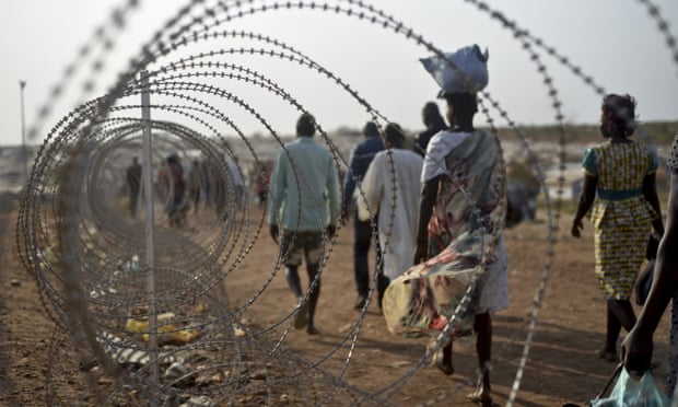 Displaced people walk next to a razor wire fence at the UN base in Juba.