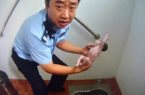 Handout image shows a Chinese policeman holding an abandoned newborn baby in a public toilet in Beijing. The newborn baby girl was abandoned and found fell head-first down the pipe.