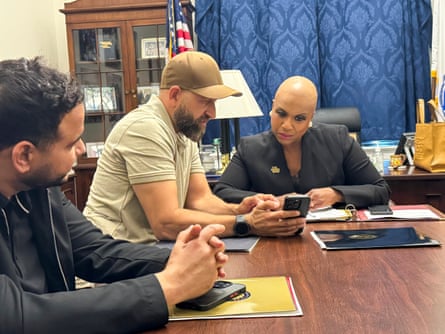 A man shows a woman videos on his phone in her congressional office