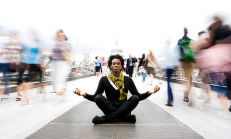 Young black man meditation on the Millennium Bridge in London while blurred people move around him