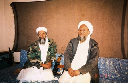 Osama bin Laden on left in white cap and robe with camouflage jacket, and his successor Ayman al-Zawahiri, also dressed in white, with a brown jacket.