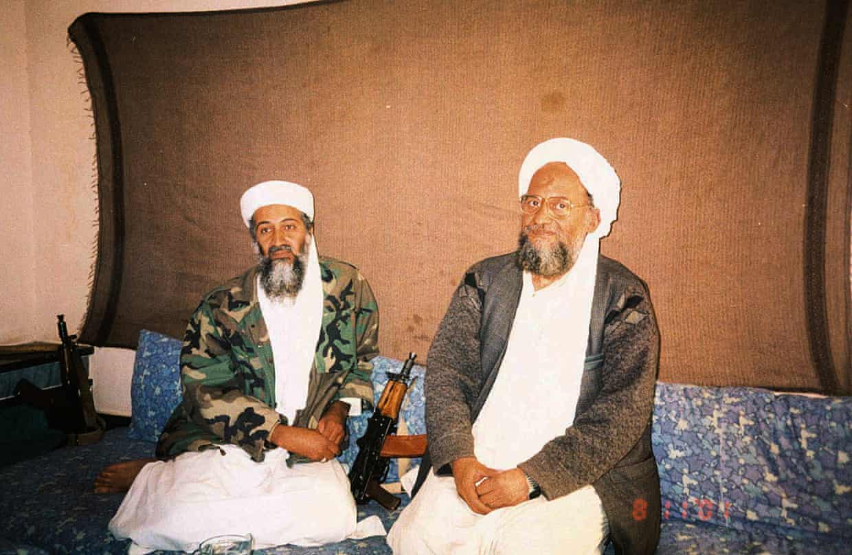 Osama bin Laden on left in white cap and robe with camouflage jacket, and his successor Ayman al-Zawahiri, also dressed in white, with a brown jacket.