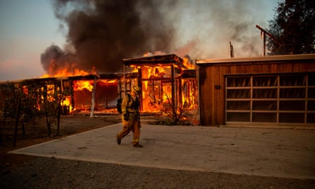 A firefighter walks by a house as it burns during the Kincade fire in Healdsburg, California, on Sunday.