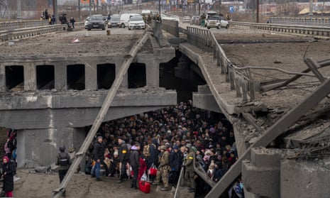 Ukrainians crowd under a destroyed bridge as they try to flee across the Irpin River in the outskirts of Kyiv, Ukraine on 5 March
