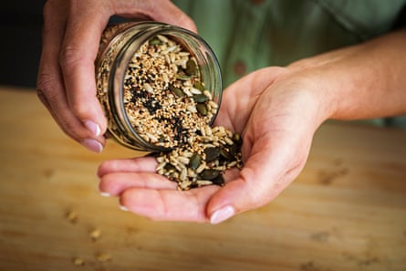 Woman pouring mixed seeds from a glass jar into her hand