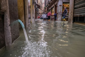 Water is drained from a store by an electric pump in Venice, Italy.