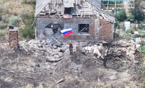 A soldier waves a Russian flag in front of a destroyed building