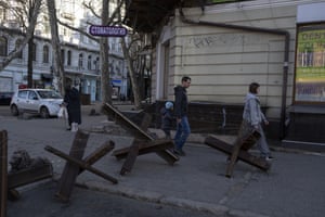 A family walks next to anti-tank barricades in Odesa, southern Ukraine