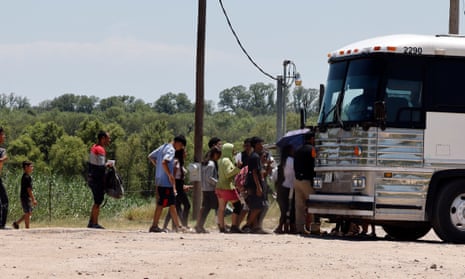 Asylum seekers go on a bus after crossing the Rio Grande River, in Eagles Pass, Texas, on 13 July. 