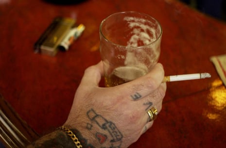 A man drinking and smoking in a pub in London