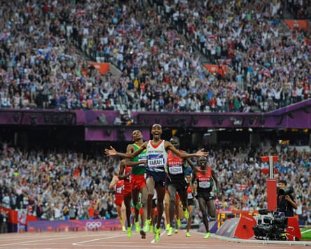 Mo Farah celebrates with arms outstretched crossing the finish line, ahead of competitors, in a packed stadium