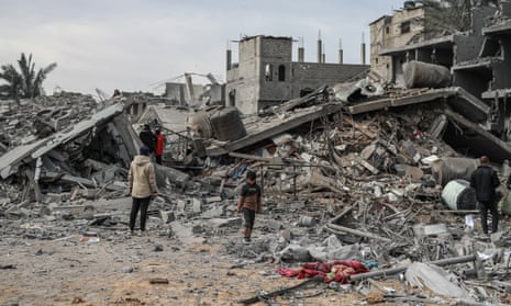 Palestinian people look at the rubble of damaged buildings after attacks in Rafah.