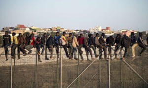 Migrants on a border fence separating Morocco from the Spanish enclave of Melilla