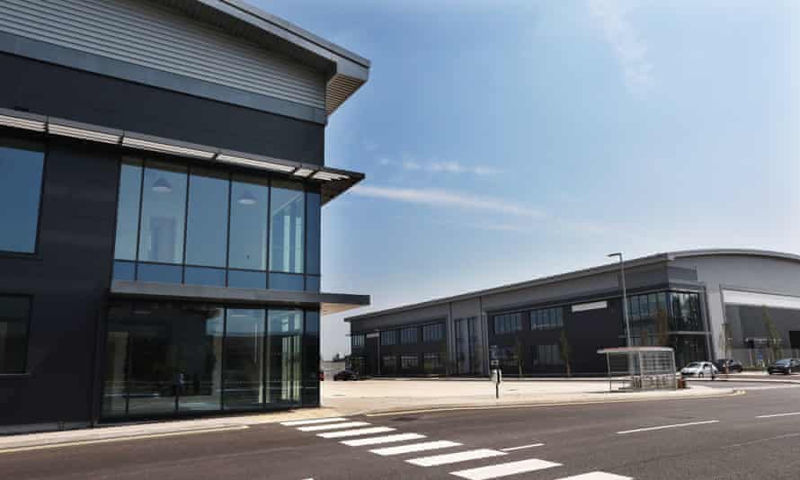 Photograph of two new-looking commercial premises in dark grey on a sunny day, with a wide, empty road in front of them
