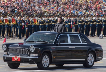 Xi Jinping rides in a black open-top car in front of parading soldiers and banks of spectators
