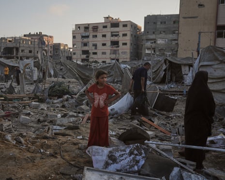 Palestinians salvage their belongings from the rubble of a building and tents destroyed in an Israeli airstrike in Gaza City, northern Gaza, on Thursday