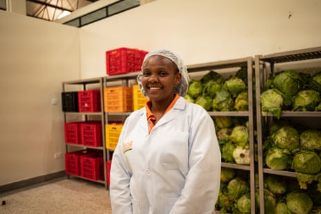 Caroline Kinuthia, the kitchen manager at Food4Education, stands in front of shelves of food in the storage facility.