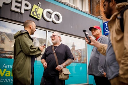 Polanski chats to a man in a black T-shirt with grey hair, wearing a shoulder bag, on the high street in Clacton-on-Sea