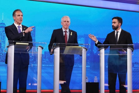 a man in a suit stands at a lectern in between two other men in suits at lecterns who are arguing with each other