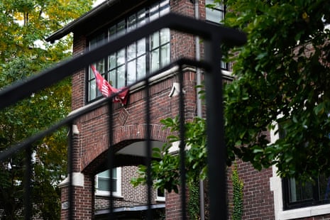 A red flag hangs from a window of the AEPi fraternity house, seen through railings and trees