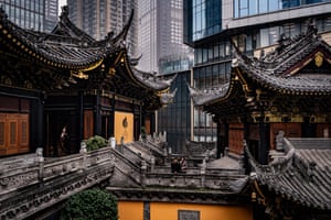 An ancient temple with modern, glass-fronted buildings behind it